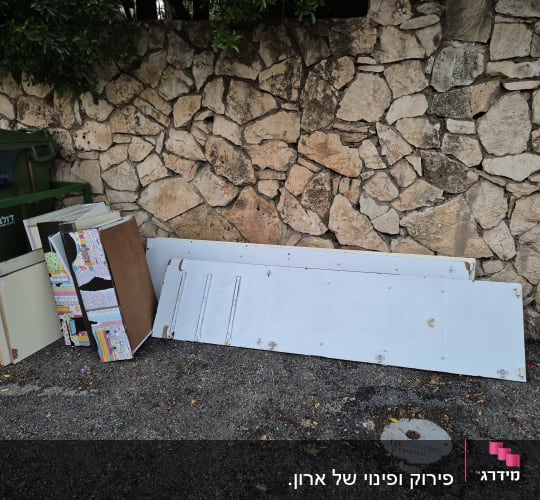 לוחות עץ וקרטון מונחים ליד קיר אבן